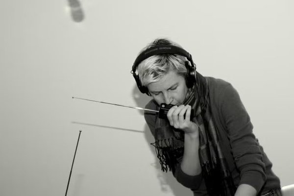 Anna Friz performing with a handheld radio and headphones